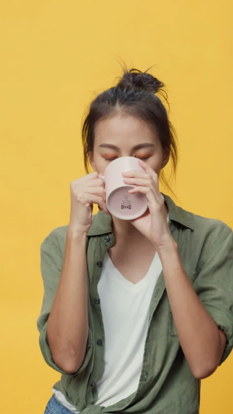 Lady hold cup of tea or coffee stand over yellow empty space background. 스톡 동영상 347196640