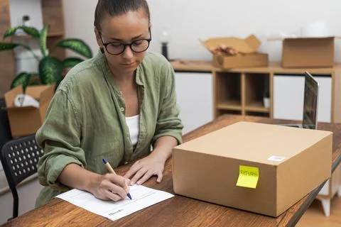 Lady, at home completes a return order form, articulating her intention to Foto stock