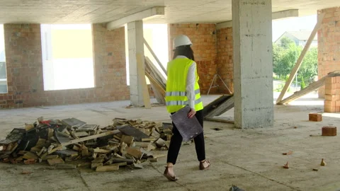 Lady inspector in hard hat and safety vest walks around work area Stock Footage 317611926