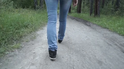 Lady in jeans walks in a forest Stock Footage
