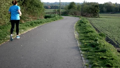 Lady jogging on a pathway in a park Stock Footage 107599208