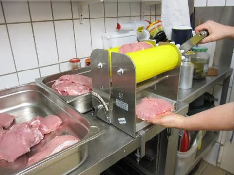 Lady in kitchen operating cutlet machine 写真素材
