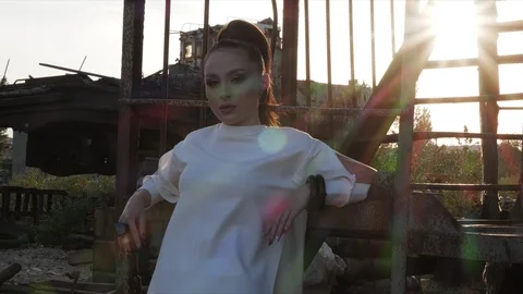 Lady leans on structure looking ahead against bright sunset Stock Footage 117887919