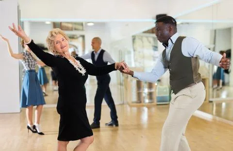 Lady learning to dance lindy hop with man in dance school Stock Photos