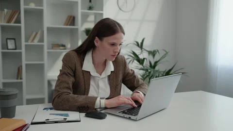 Lady Manager Comparing Accounts from Laptop and Looks at Graphs While Sitting in Stock Footage 263882889