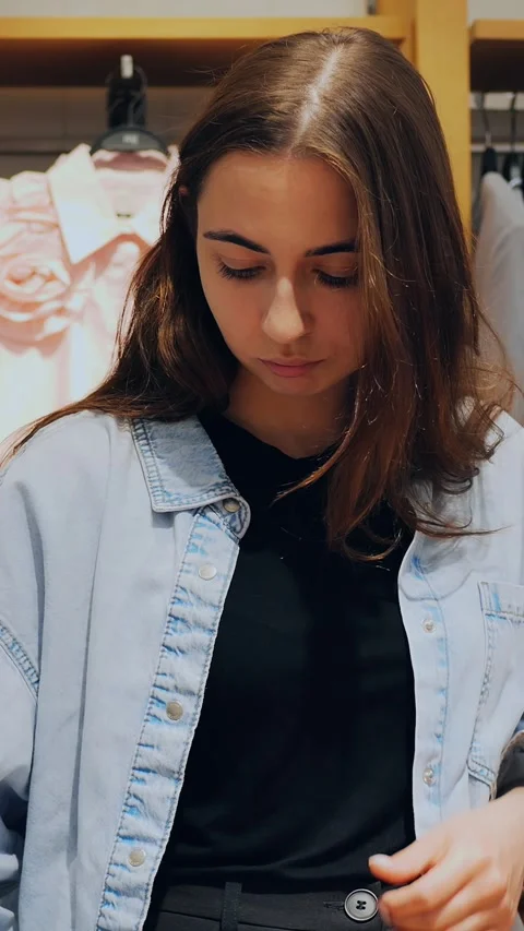 Lady methodically evaluates fabric and apparel inside retail store environment Stock Footage 344743317