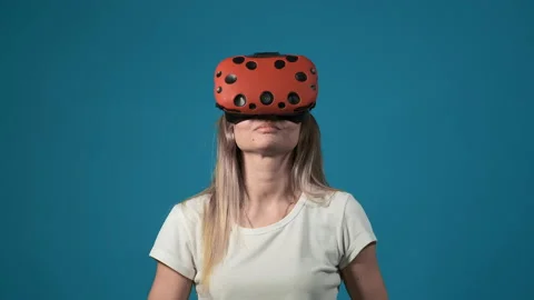 Lady with orange virtual reality headset screams at blue wall 库存影片 130894259