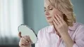 Lady over 50 looking at herself in mirror, rejoicing at result of skin lifting 4k or 4k+ Resolution