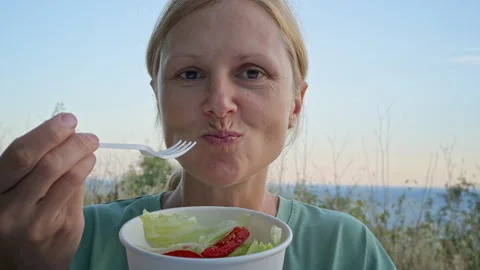 A lady partakes in a repast of raw vegetable salad at a picnic. Stock Footage 282176212