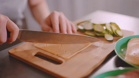 Lady Preparing Cheese Slice with Fresh Cucumber on Cutting Board Video stock 328353990