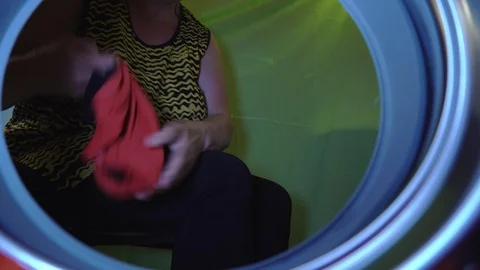 A lady putting up the clothes inside the laundry machine Stock Footage 95387384