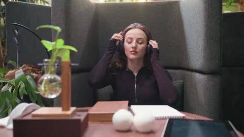 Lady Putting On Headset And Opening Book On Table With Indoor Plant Decoration Video stock 310699481