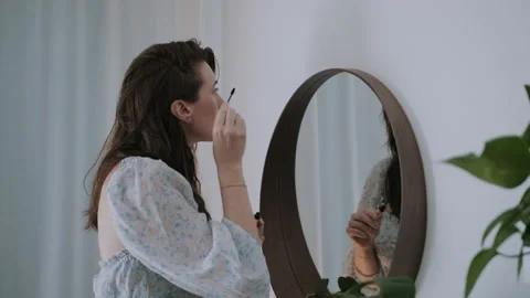 Lady putting on mascara while looking at herself in the mirror Video stock 132365731