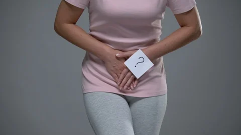 Lady with question mark sign on her hand touching belly, cystitis, dysmenorrhea 動画素材 117185462
