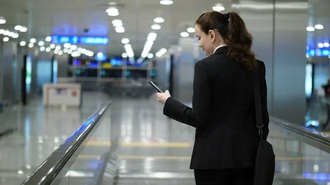 Lady read information using mobile device, stay on moving travellator Stock Footage 90311027