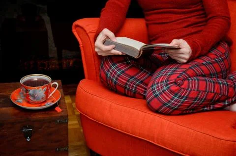 Lady reading and drinking tea by the fireplace Stock Photos