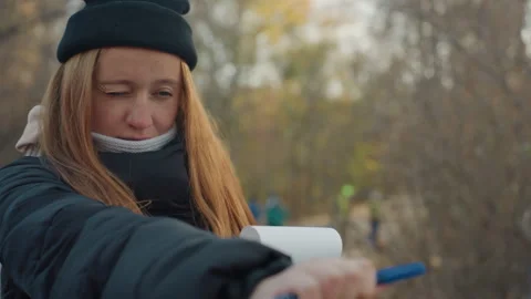 Lady recording insights in fall park setting. Woman engrossed in note taking 스톡 동영상 332042773