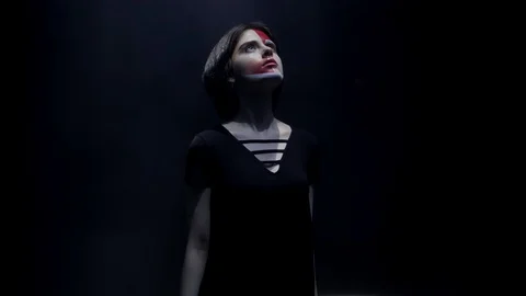 Lady with red paint on face at light beam in dark space Stock Footage 114954824