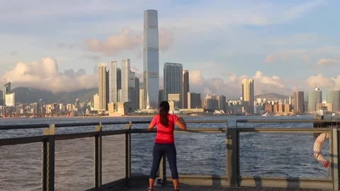 Lady in red shirt does simple exercise at the water front near Central Wester Stock Footage 155540435
