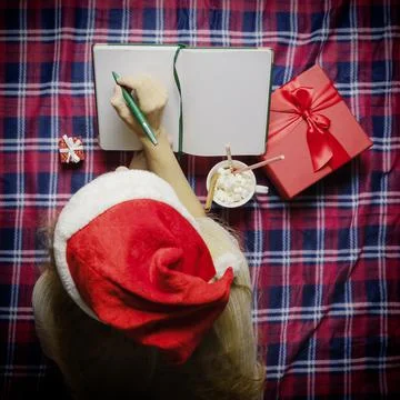 Lady santa taking notes in a diary while lying in a cozy home environment Stock Photos