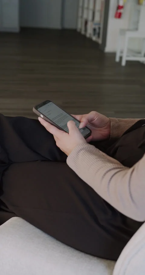 Lady scrolling through text messages comfortably, Female seated on sofa engaged Video stock 322630862