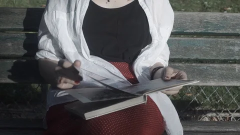 Lady seats at the bench reading book Stock Footage
