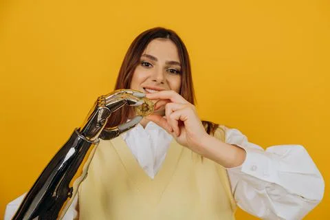 Lady with shiny bionic arm holds golden bitcoin on yellow Stock Photos