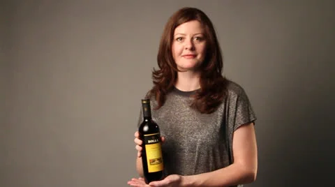 Lady shows a cherry wine bottle and give pose for camera Stock Footage 22935252