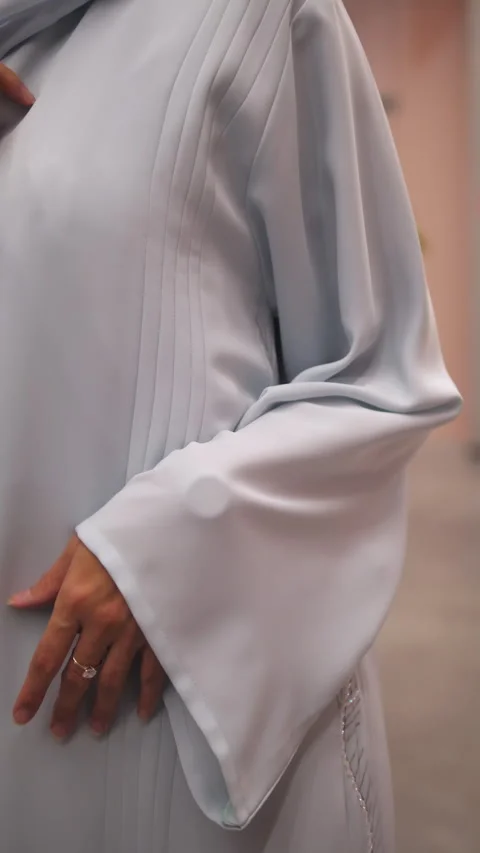 Lady shows pattern on Abaya unobtrusively correcting fabric Stock Footage 330189381