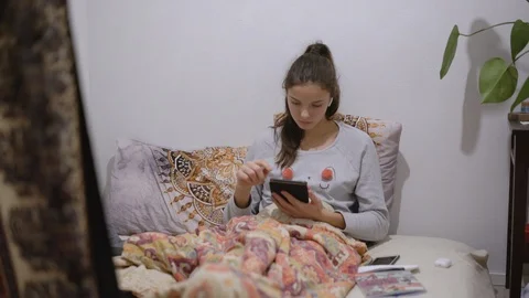 Lady sits on bed under blanket and types on modern tablet Video stock 121835091