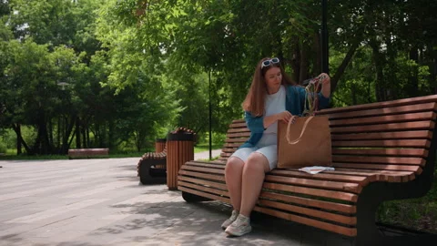 Lady Sitting On Park Bench Bringing Out Embroidery Material From Bag Stock Footage 326030778