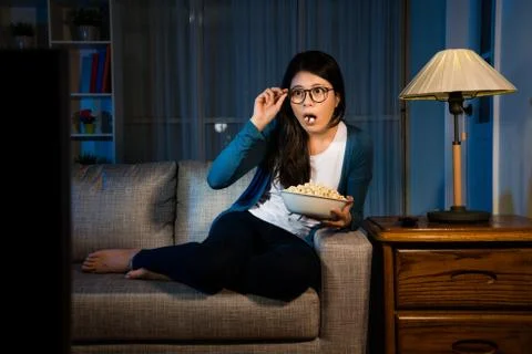 Lady sitting on sofa couch looking at television Фото