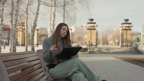 Lady sketching ideas with tablet amidst city scene. Young woman working on Stock Footage 342431414