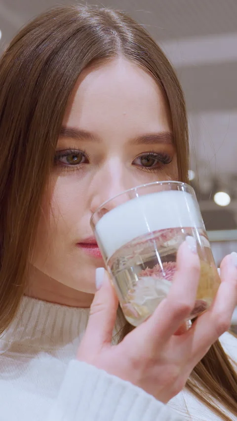 Lady smelling perfume in mall store with other shoppers in background Stock-Footage 325787002