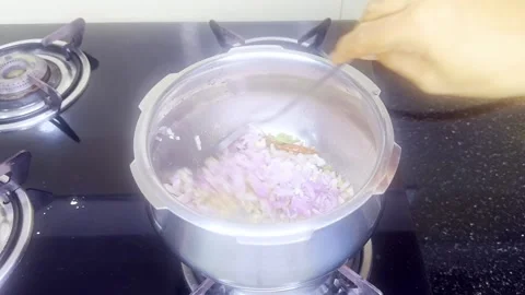 Lady stirs diced ingredients inside steel pot on burner Stock Footage 313277097