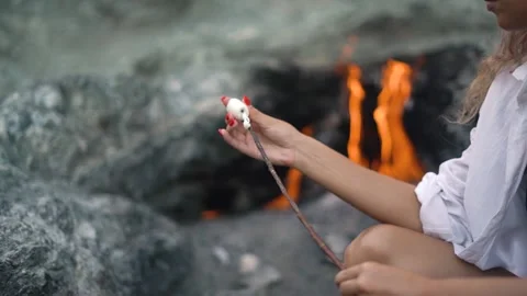 Lady strings marshmallows against Chimaera mountain flame Video stock 143341373