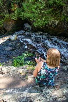 Lady taking a picture of a river with her smartphone, Vertical Stock Photos
