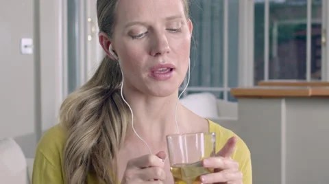 Lady taking a sip of Herbal tea while at home listening to music through her Stock Footage 63032040