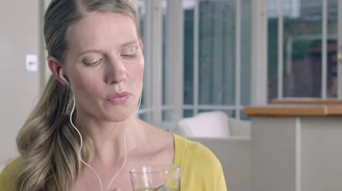 Lady taking a sip of Herbal tea while at home listening to music through her Stock Footage 63032583