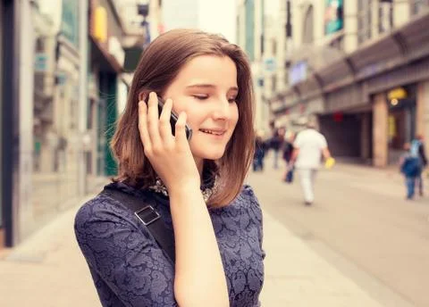 Lady talking on the mobile phone while walking on a street in summer Stock Photos