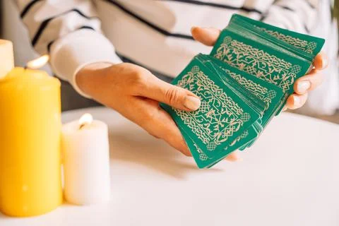 Lady tarot reader shuffles tarot cards in front of candles Stock Photos