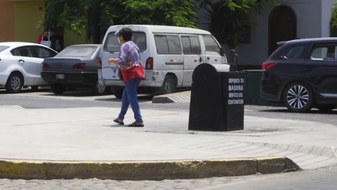A lady throwing her garbage in a container on the street with a mask Vidéo 149903246