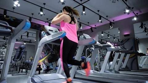 Lady in top stops running on gray treadmill backside view Stock Footage 104235736