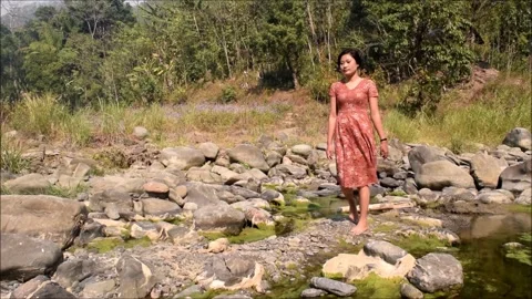 Lady trying to cross a river stream barefoot 動画素材 158124620