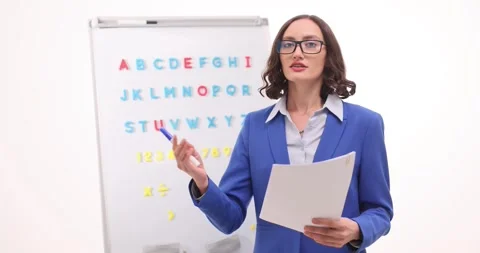 Lady tutor holds document and explains key points of lesson Stock Footage 294312300