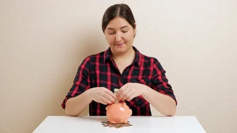 Lady twists and inserts dollar banknote into piggy bank slot Stock Footage 147596926