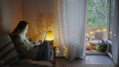 Lady types on laptop sitting on sofa in stylish room Stock Footage 164839707