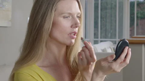 Lady uses mobile Phone while applying make up Stock Footage 63032108