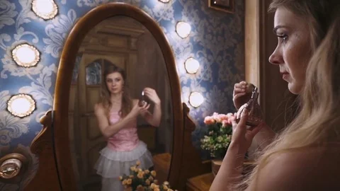 Lady uses perfume, in front of a mirror, vintage room interior. Stock Footage 79740813
