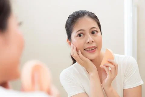 Lady using cosmetic sponge finishing face makeup 스톡 사진